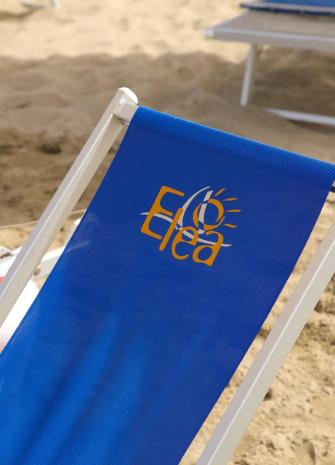 Chaise longue bleue avec logo Elea sur la plage.