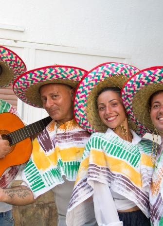 Groupe en tenues mexicaines traditionnelles avec sombreros colorés et guitare.