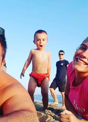 Famiglia felice in spiaggia con bambino entusiasta.