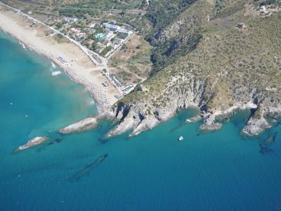 Luftaufnahme eines Strandes mit Felsen und blauem Meer.