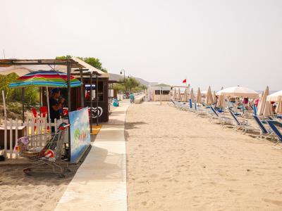 Plage de sable avec parasols, transats et kiosque.