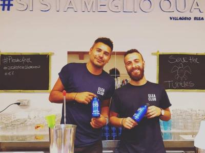 Deux hommes au bar avec des t-shirts Elea Club, promeuvent des bouteilles durables.