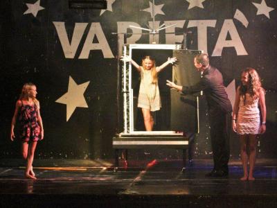 Spectacle de magie avec des filles et un illusionniste sur scène.