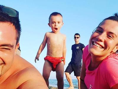 Famiglia felice in spiaggia con bambino entusiasta.