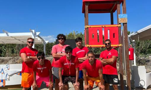 Bagnini in posa davanti a una torretta sulla spiaggia.