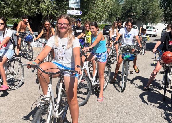 Gruppo di ragazzi in bicicletta sotto il sole, giornata estiva.