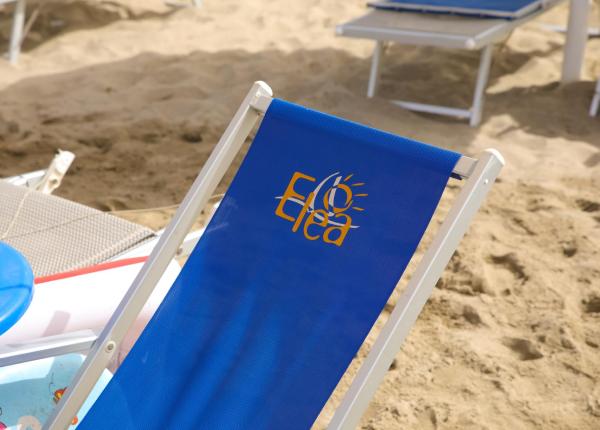 Chaise longue bleue avec logo Elea sur la plage.