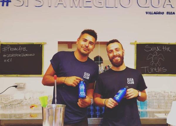 Deux hommes au bar avec des t-shirts Elea Club, promeuvent des bouteilles durables.