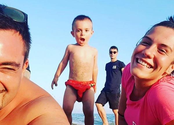 Famiglia felice in spiaggia con bambino entusiasta.