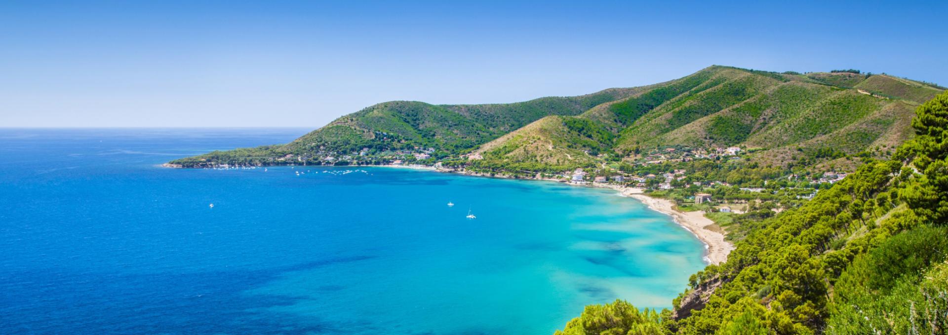 Spiaggia con mare cristallino e colline verdi, ideale per una vacanza rilassante.