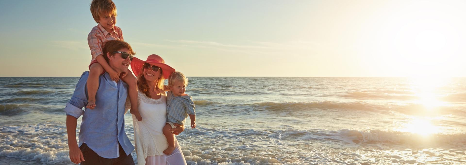 Famiglia felice in spiaggia al tramonto, con due bambini e un'atmosfera serena.