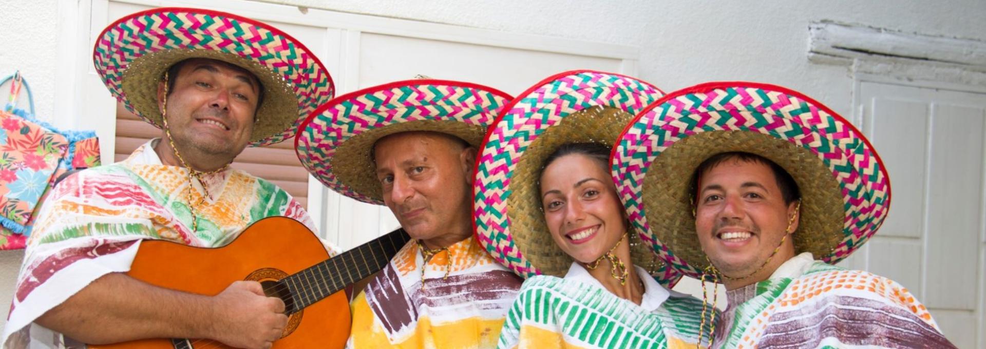 Gruppo di persone con sombreri colorati e poncho, uno suona la chitarra.