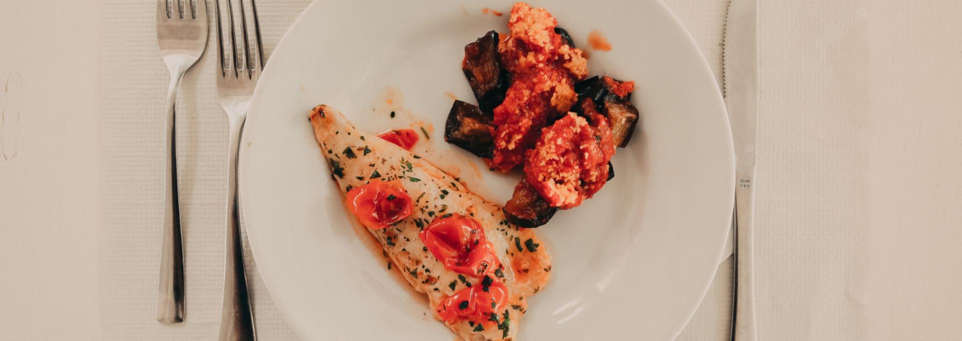 Filetto di pesce con pomodorini e contorno di verdure al sugo.