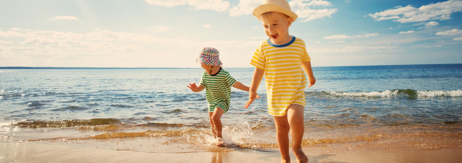 Bambini felici giocano in riva al mare sotto il sole estivo.