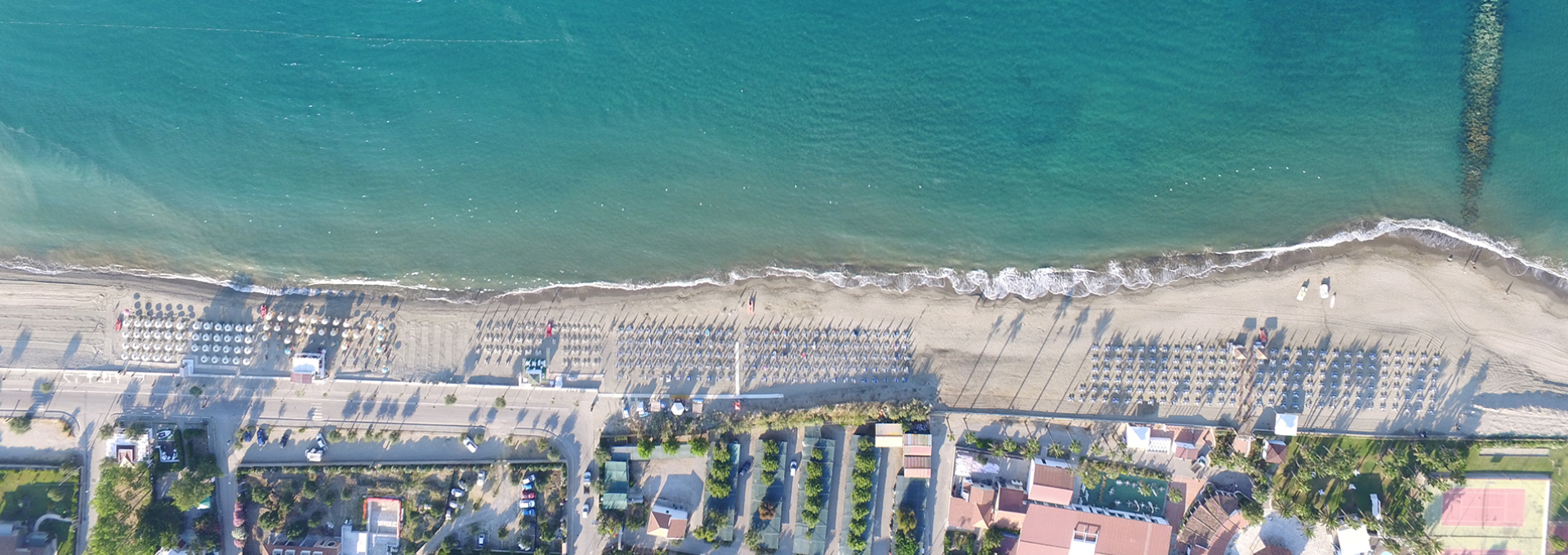 Vista aerea di una spiaggia con ombrelloni e mare cristallino.