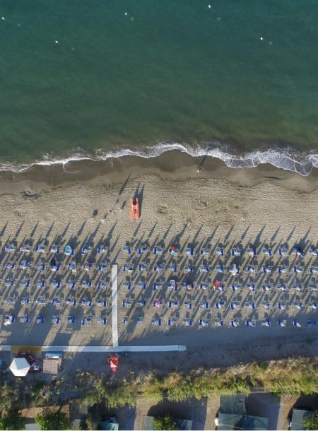 Spiaggia con ombrelloni e sedie a sdraio, vista dall'alto, vicino al mare.