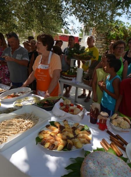 Festa all'aperto con tavolo imbandito di cibo e persone che osservano.