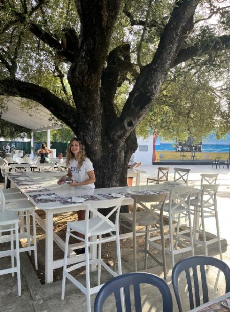 Ragazza seduta a un tavolo all'aperto sotto un grande albero.