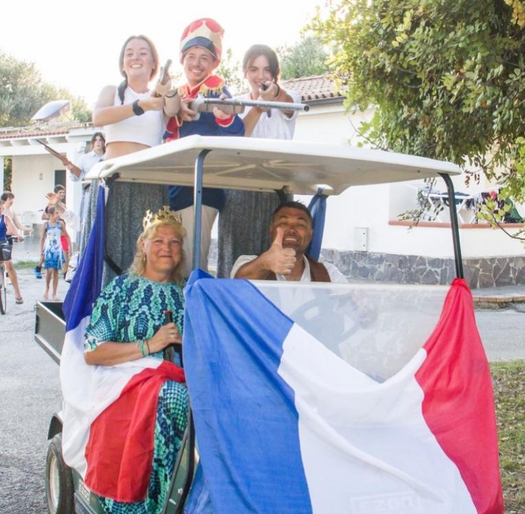 Persone in costume su un carrello da golf con bandiera francese.