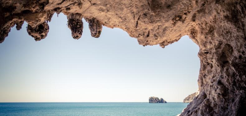 Vista dall'interno di una grotta verso il mare, con un'isola in lontananza.