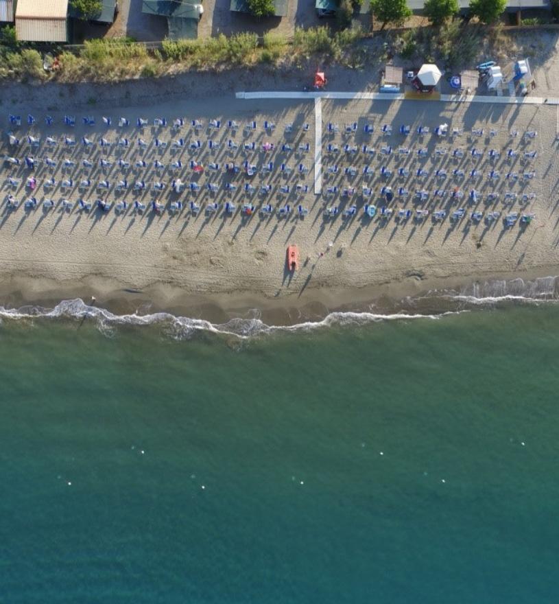 Spiaggia con ombrelloni allineati, mare calmo e cabine sulla riva.